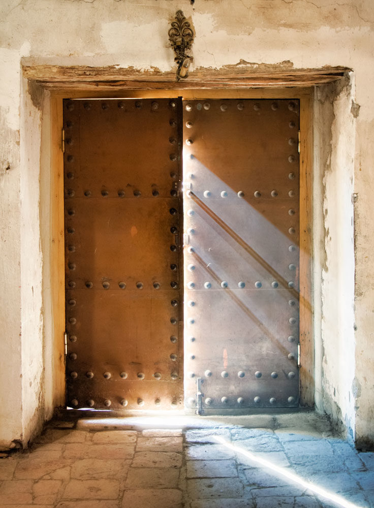 The church door almost close with light rays falling down to the